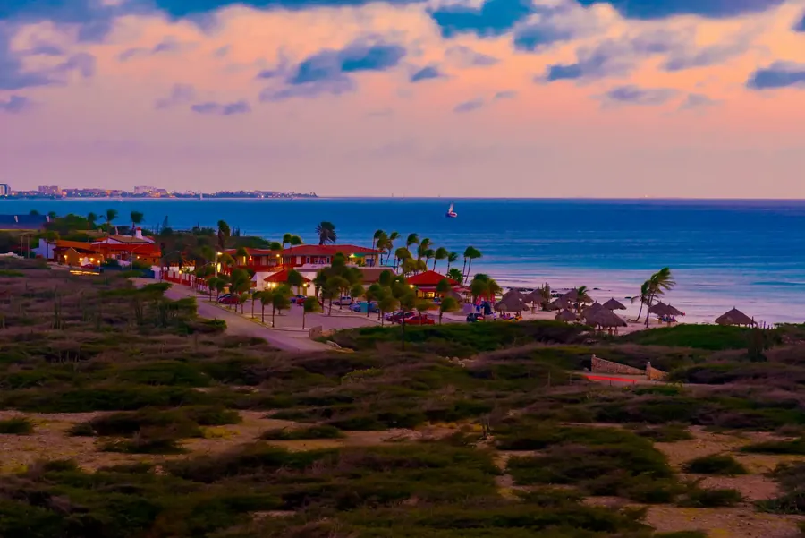 The coast of Aruba at sunset with a long beach and turquoise water