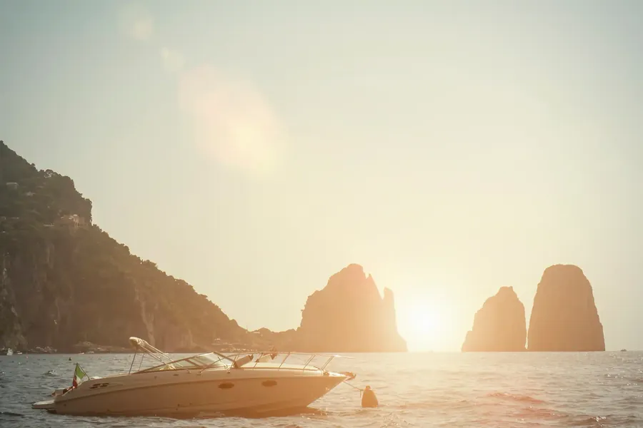The Faraglioni rocks of Capri at sunset with a boat passing