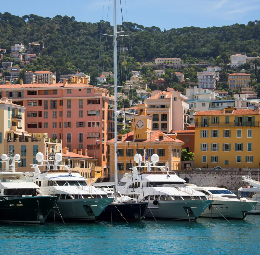 The old port of Nice with ochre houses, boats and hills behind