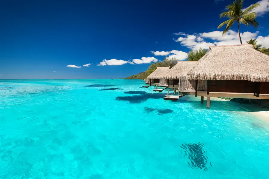 Beach villas among palms with steps into a turquoise lagoon in the Maldives