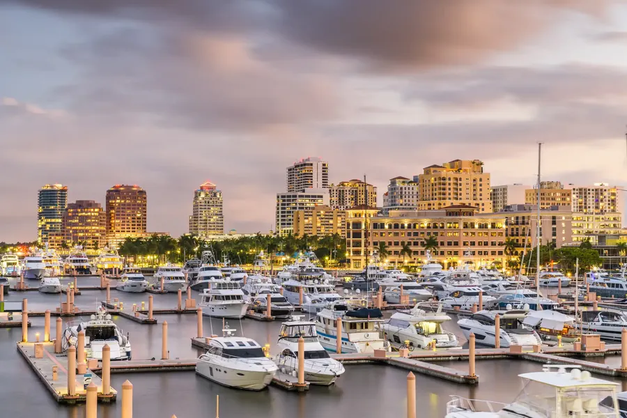 The West Palm Beach skyline across the water with palms and a marina