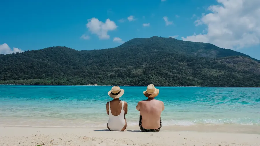 Koh Lipe with turquoise water, a longtail boat and a green island behind