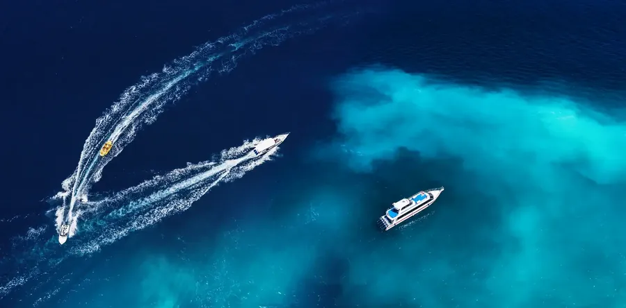 Speedboats crossing a deep blue sea near Bali, seen from above