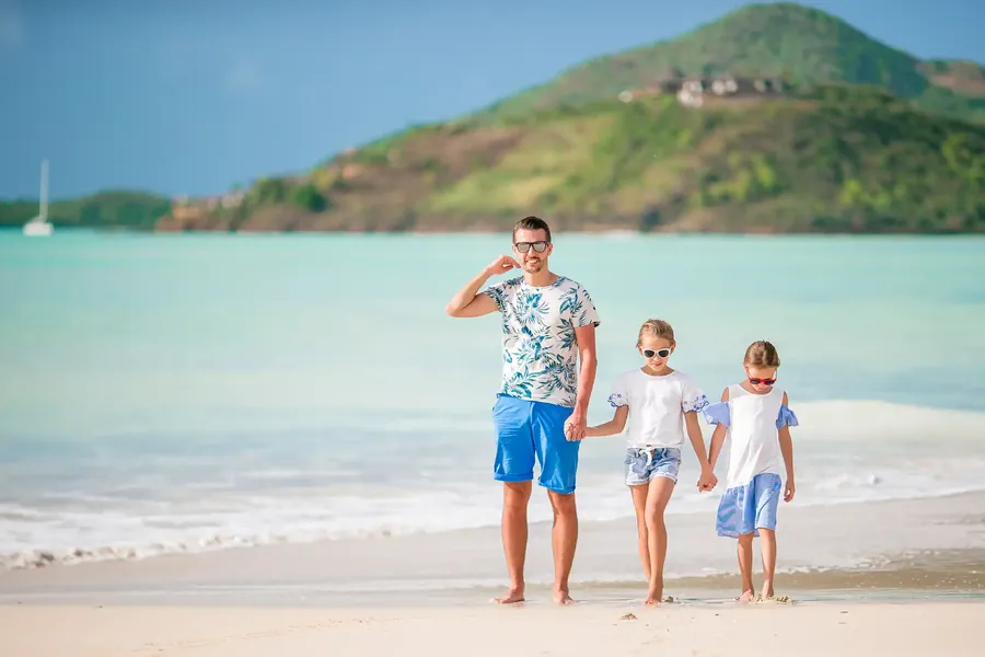 A father walking on a beach with his two daughters